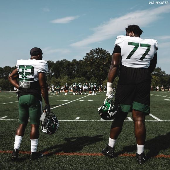 Large Human Football Player Mekhi Becton Photographed Next to Much Smaller Teammate